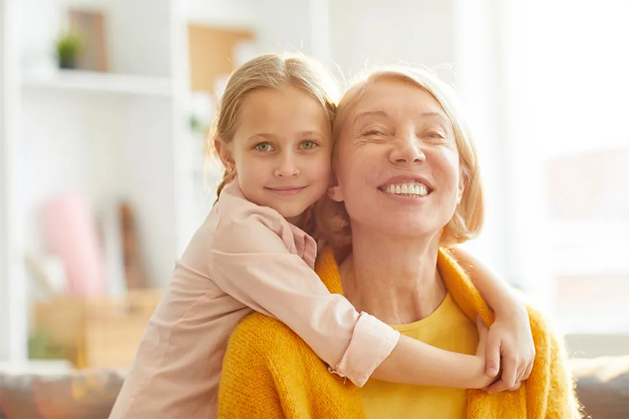 Внучка и баба, които се прегръщат с усмивка
