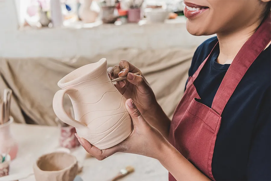 Дама по време на курс по грънчарство, оформяща керамичен съд