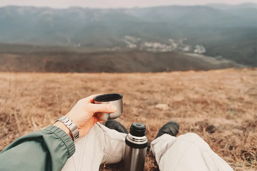 мъж се готви да пие кафе от термос